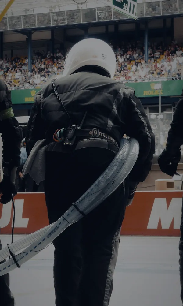 Mecánicos de boxes con la manguera de repostaje en el pit lane