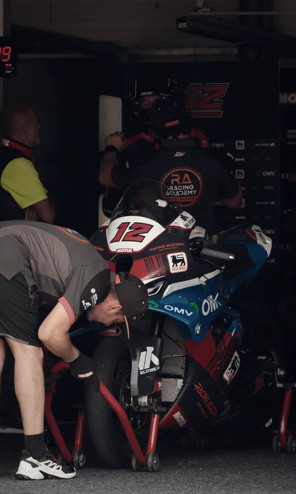 Mecánicos de un equipo trabajando en una moto de carreras en el box