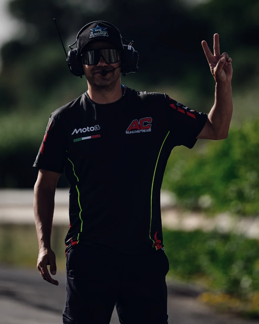 Nico Ferreira en pista con auriculares de radio, saludando
