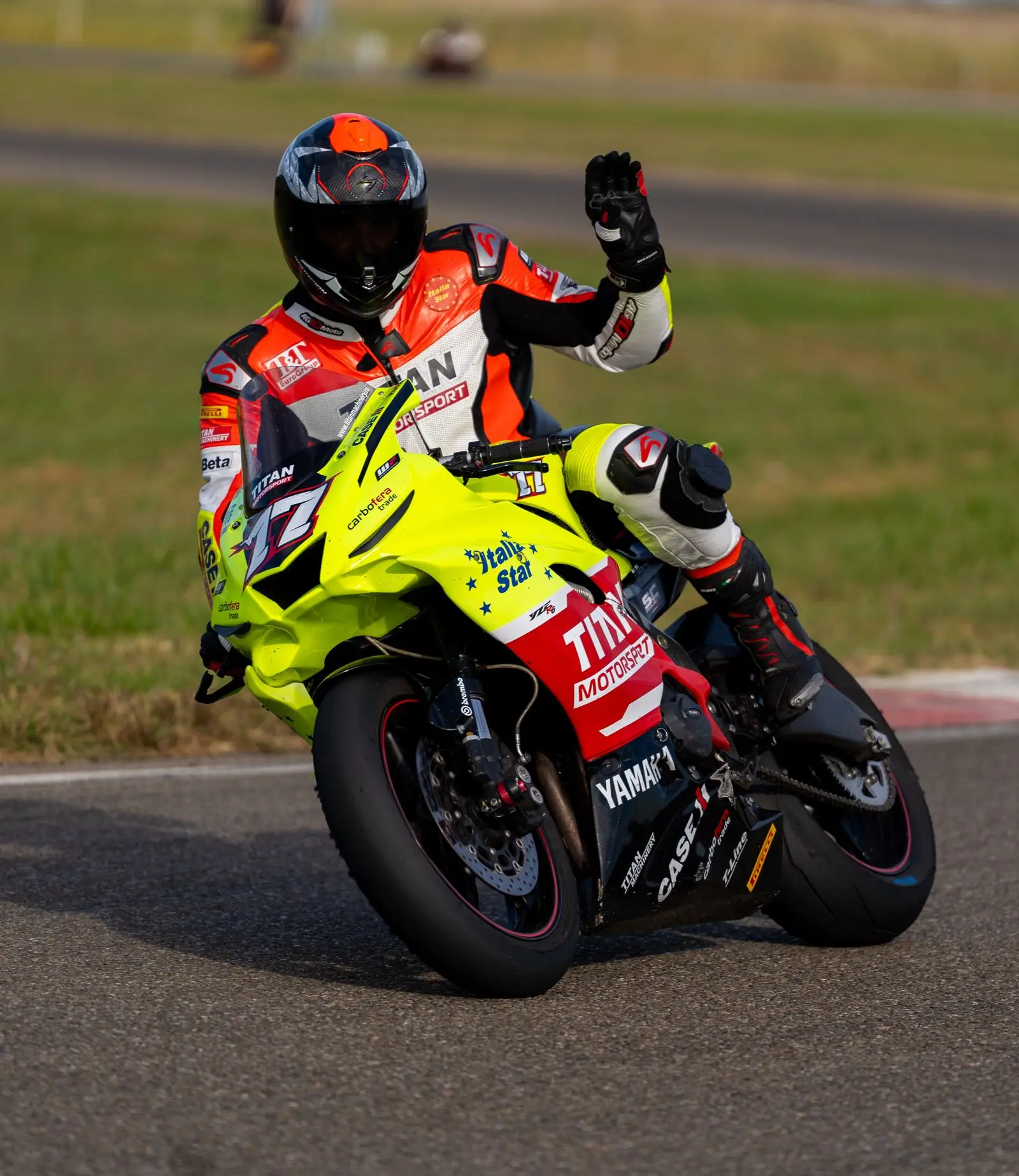 Piloto saludando desde su moto amarilla al terminar la tanda